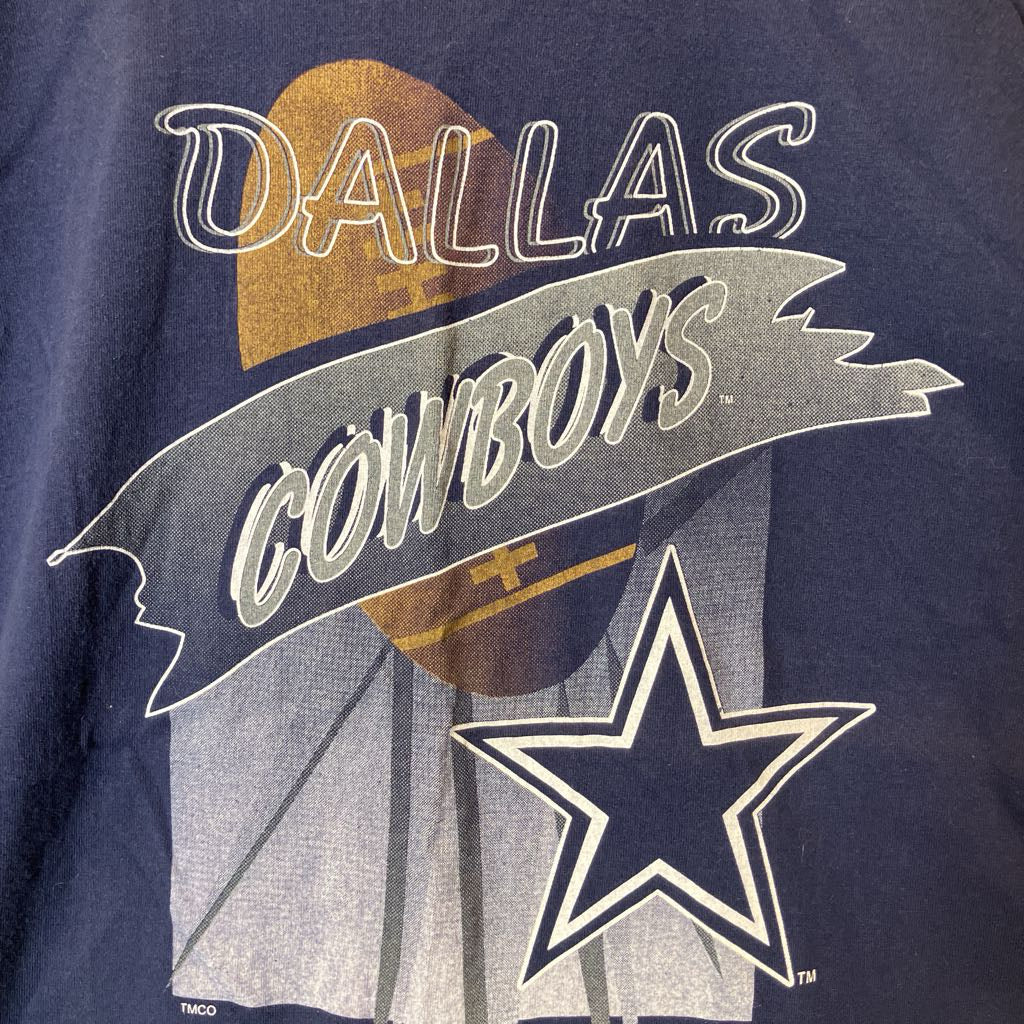 Close-up of a navy blue Dallas Cowboys graphic print featuring a large white outlined star, a gray banner with 'COWBOYS' in white script, and a gold football graphic with 'DALLAS' above it.