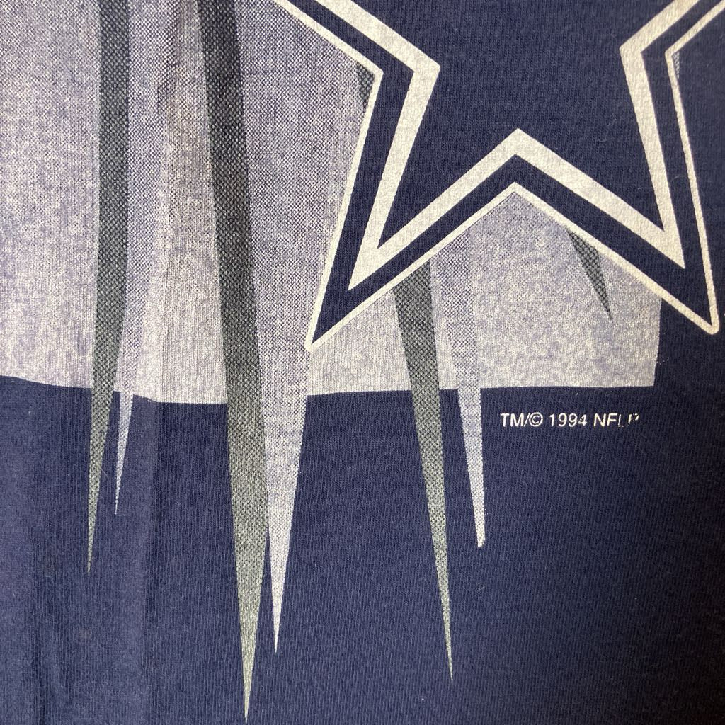 Close-up of a navy blue graphic print featuring a large white outlined star, vertical gray streaks, and small white text reading TM© 1994 NFL, P.