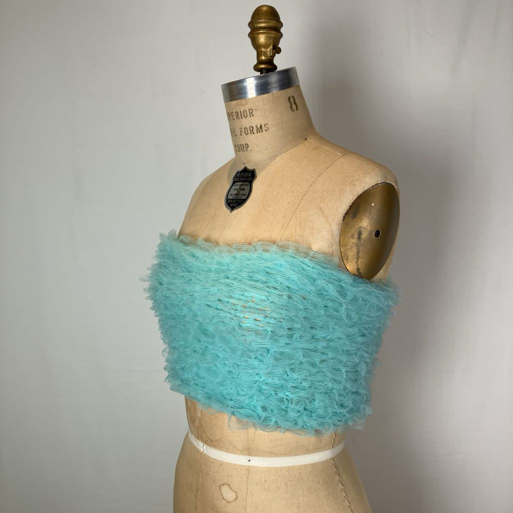 A turquoise fuzzy knit bandeau top displayed on a vintage wooden dress form mannequin against a plain light gray background.