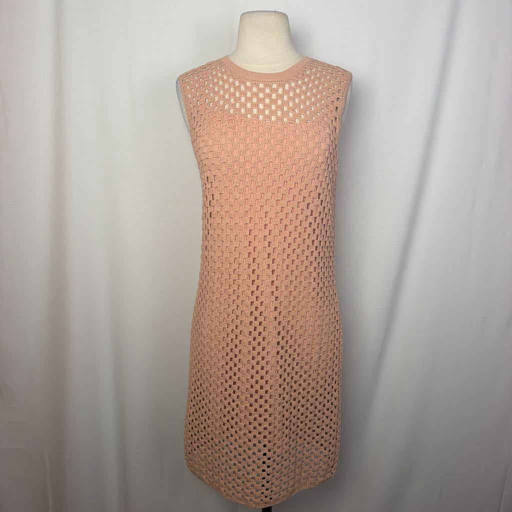 A sleeveless peach-colored knit dress with an openwork mesh pattern, displayed on a cream mannequin torso against a white fabric backdrop.