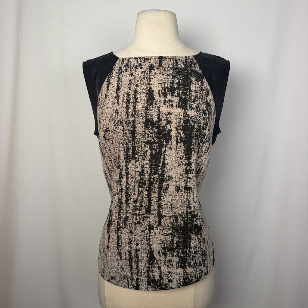 A black and white abstract sleeveless top on a mannequin in front of a white wall. 