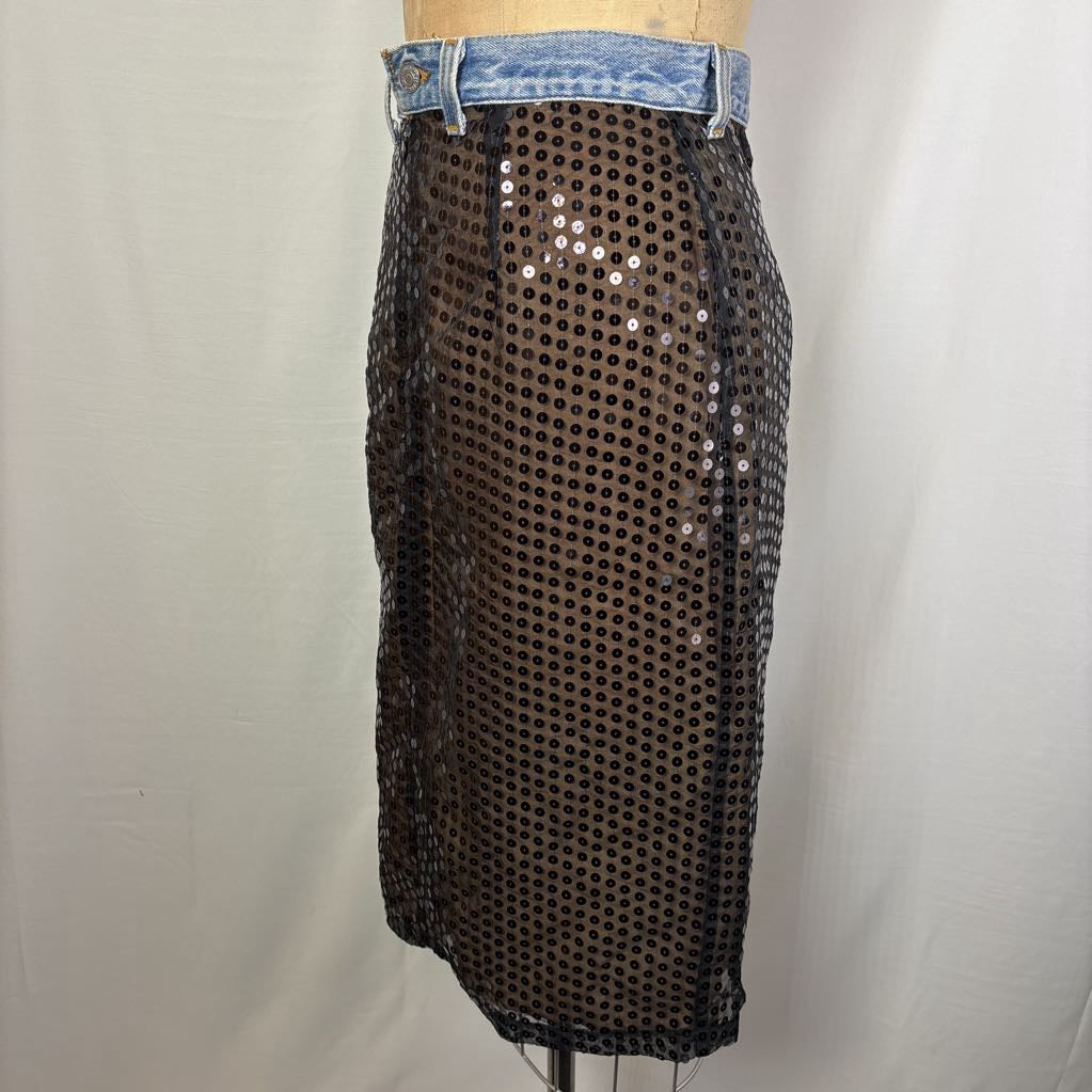 A black sequined mesh pencil skirt with a light blue denim waistband, displayed on a mannequin torso against a white fabric backdrop.