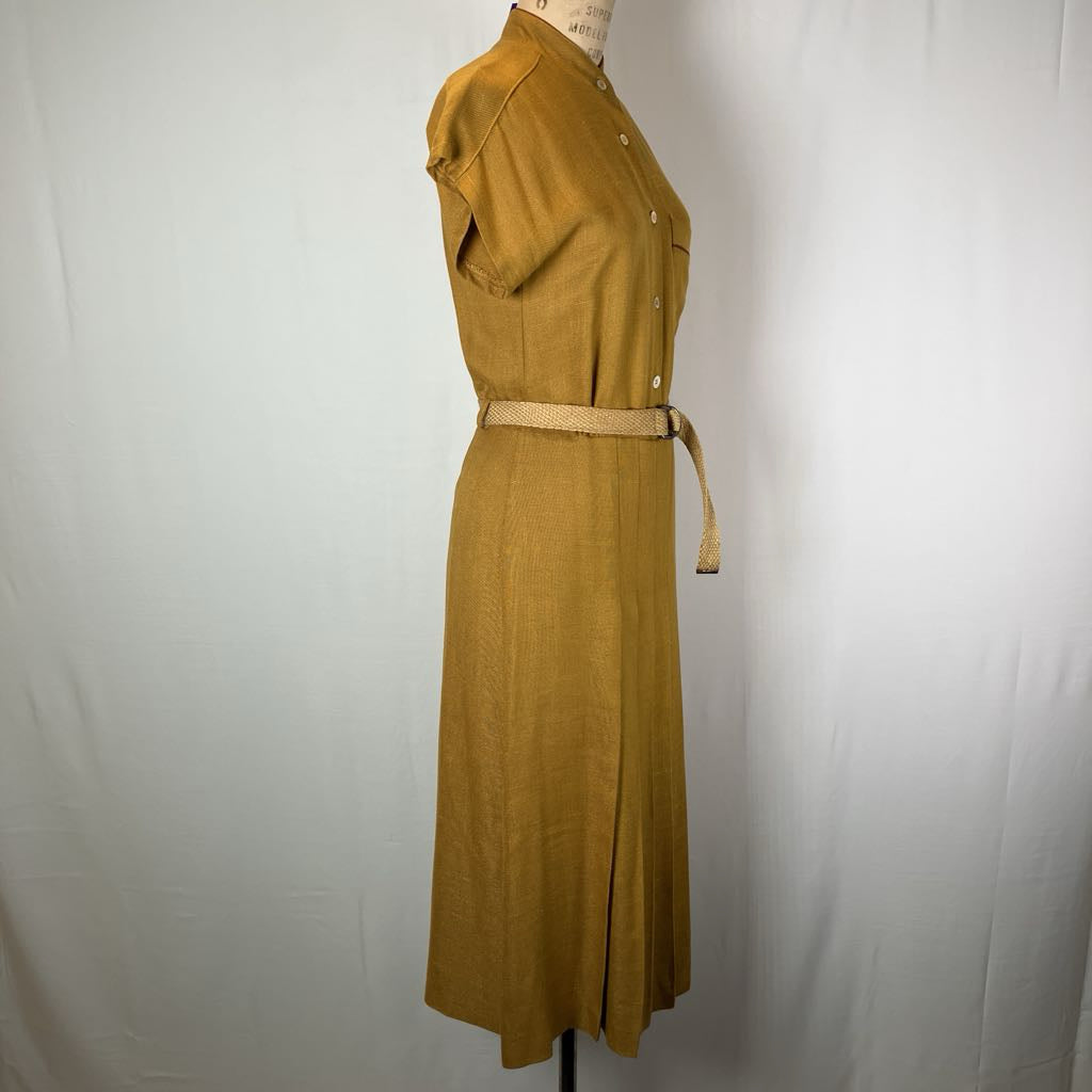 A mustard yellow linen shirt dress displayed on a mannequin against a white fabric backdrop. The dress features a button-down front, short sleeves, and a matching tan woven belt at the waist.
