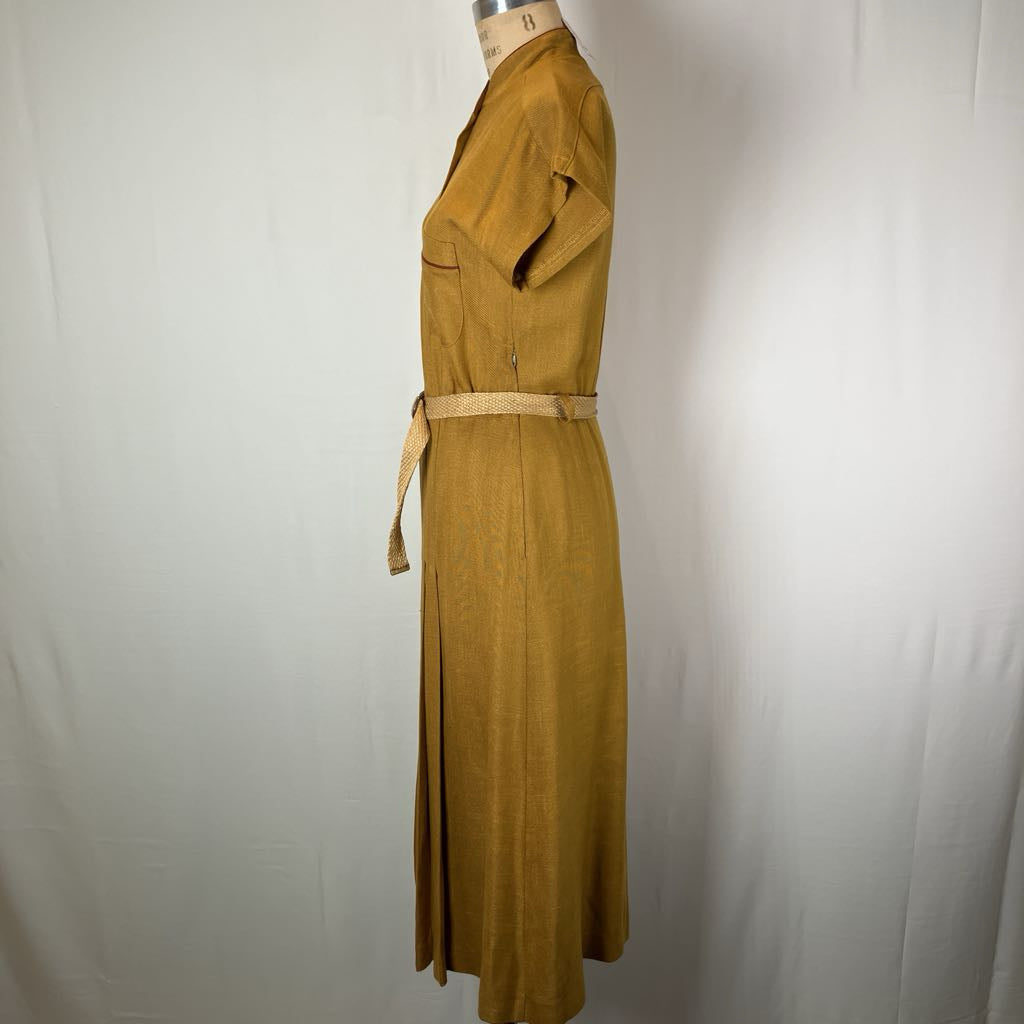 A mustard yellow linen dress displayed on a mannequin against a white fabric backdrop. The dress features a shawl collar, short sleeves, a matching waist tie belt, and a vertical front slit.