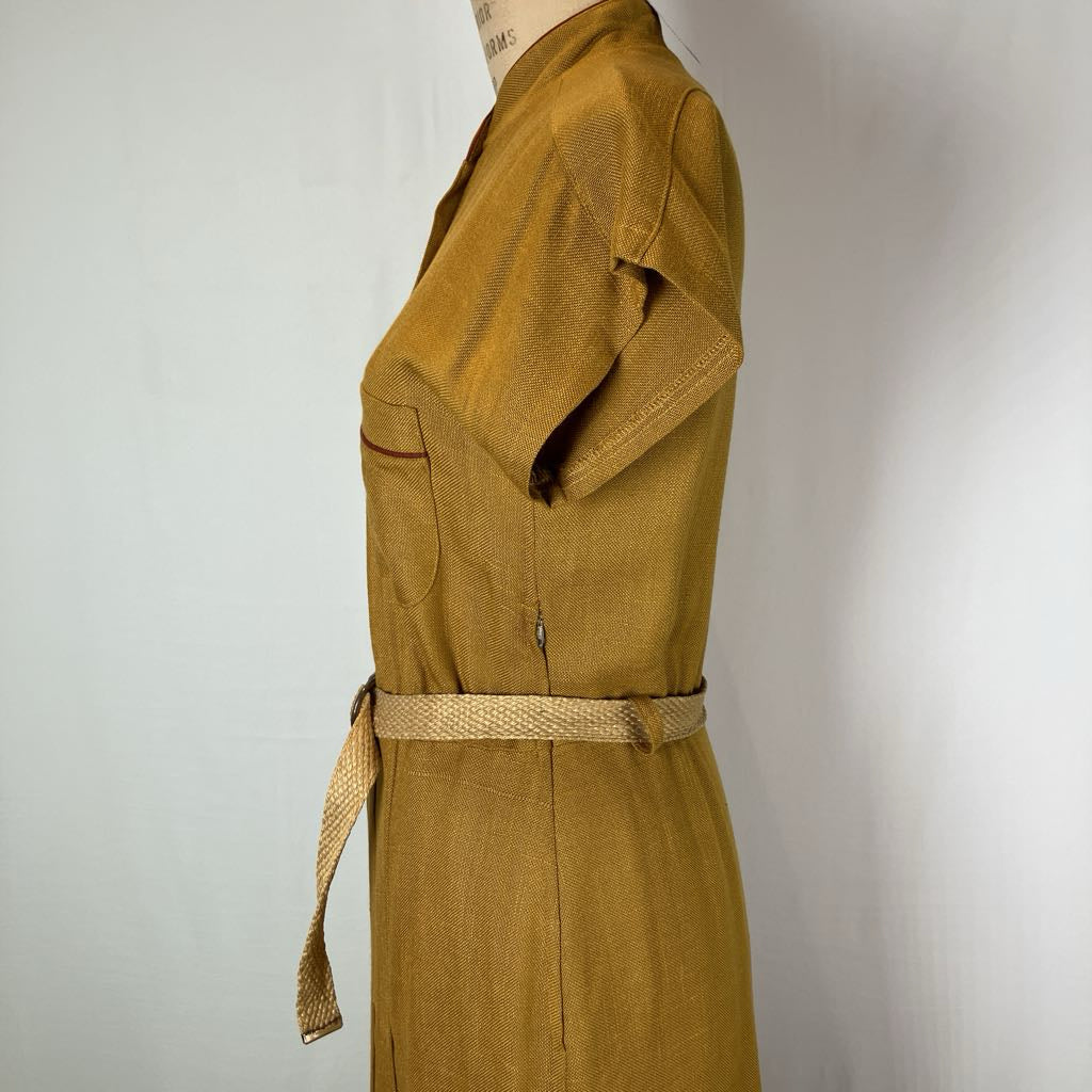 A mustard yellow linen dress displayed on a mannequin, featuring a short sleeve, a matching woven belt, and a side zipper, photographed against a plain white background.