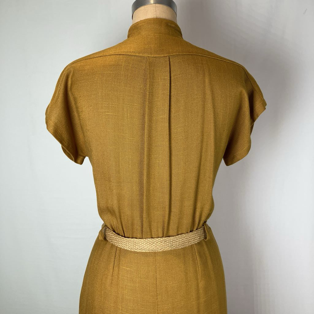 A mustard yellow linen dress shown from the back on a mannequin, featuring a high mock neck, short sleeves, a center back seam, and a matching woven belt at the waist.