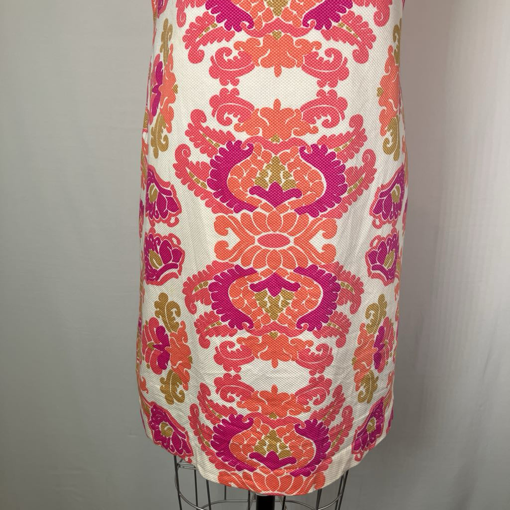 A sleeveless dress or tunic with a bold vertical damask-style floral pattern in bright pink, coral, and magenta on an off-white background, displayed on a wire dress form against a light gray backdrop.