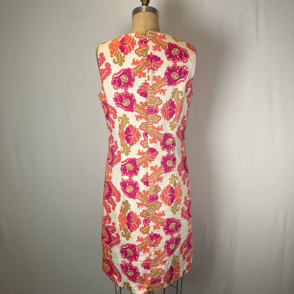A sleeveless fit-and-flare dress displayed on a dress form, featuring a vibrant pink, orange, and gold floral pattern on a cream background.