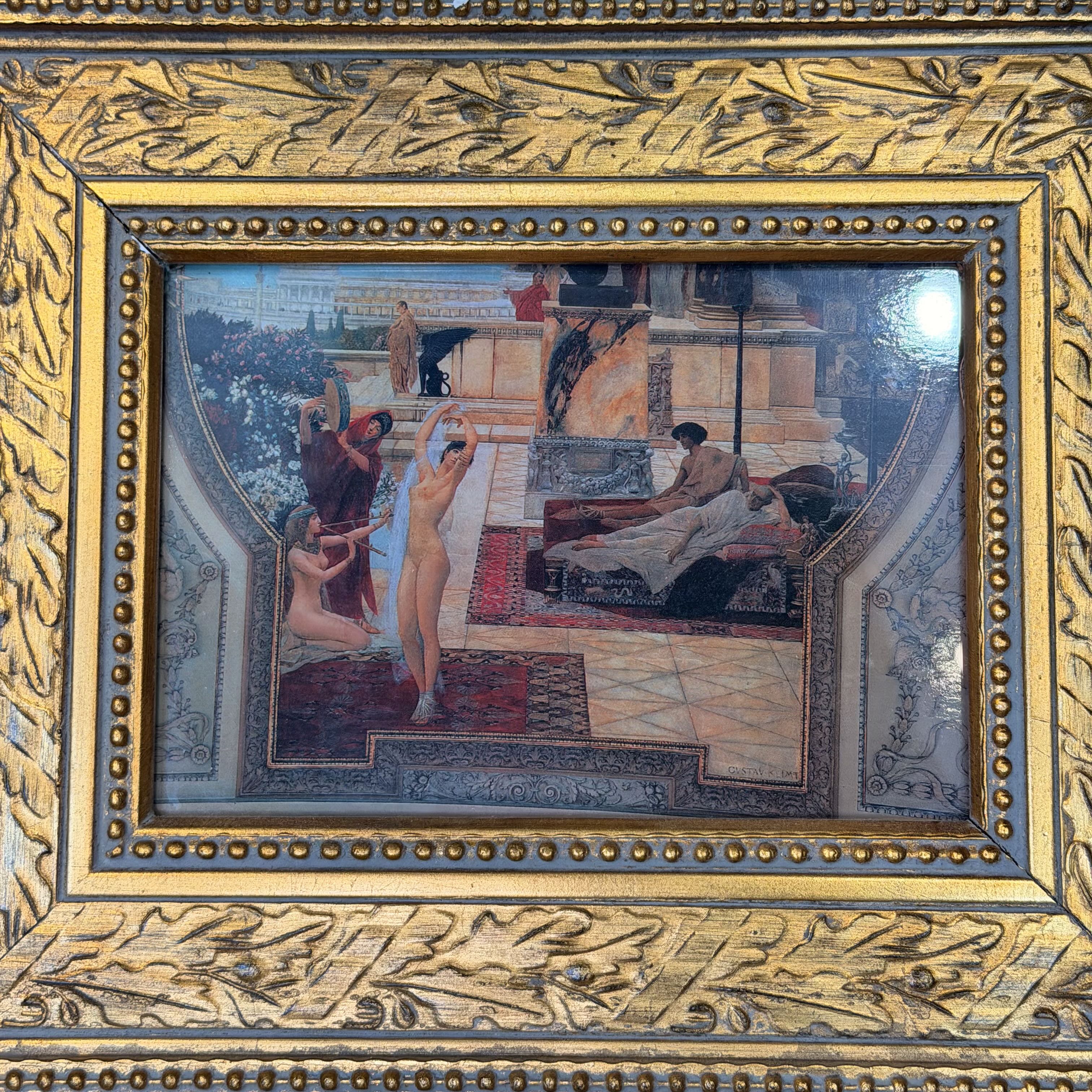 An ornate gold-toned framed artwork featuring a classical scene with several nude figures in an interior setting, surrounded by detailed carved floral and scroll motifs.
