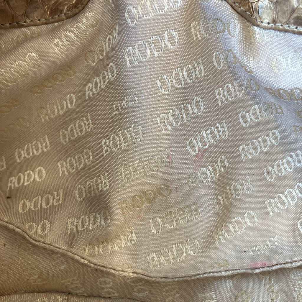 Close-up of a beige satin-like fabric with an allover woven RODO monogram pattern.