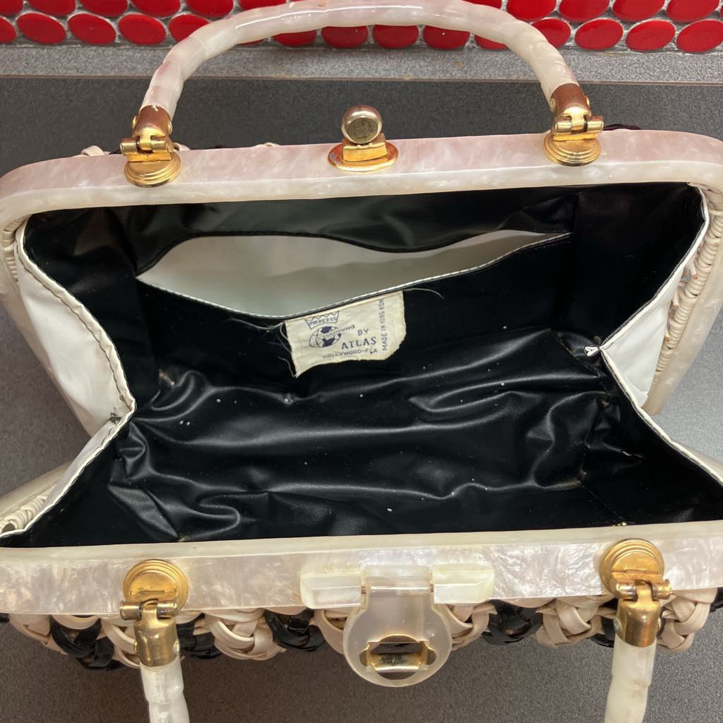 An open vintage-style handbag with a glossy black satin interior, cream-colored woven exterior, and gold-tone hardware. A sewn-in label reads 'Handbag by ATLAS'.