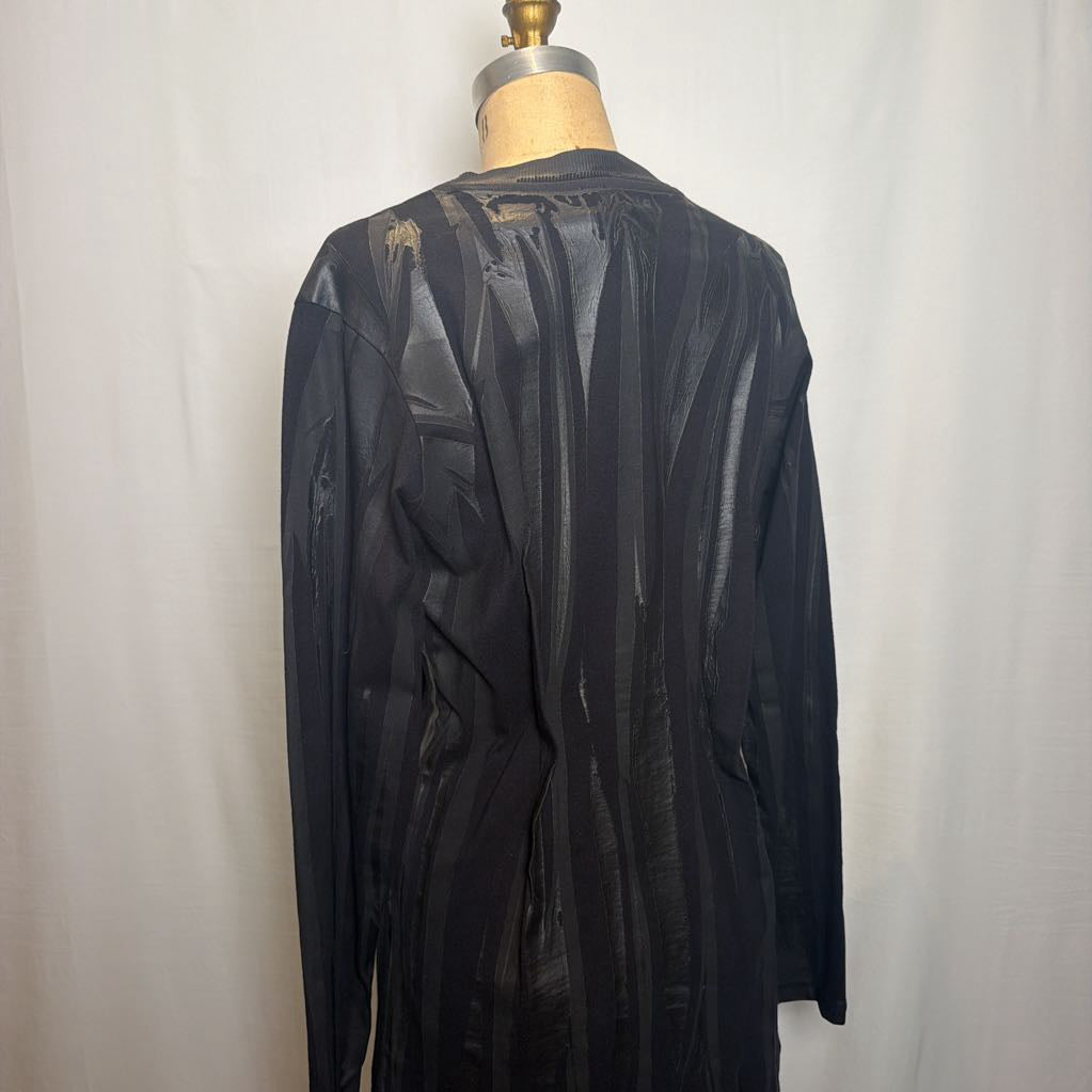 A black sheer long-sleeve top displayed on a dress form mannequin against a white fabric backdrop.