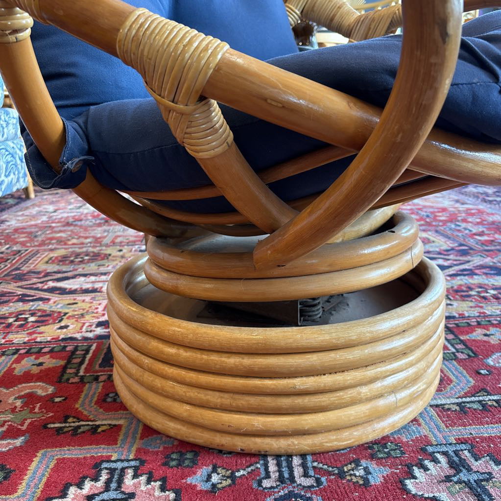 The bottom of a rattan swivel chair on a red patterned rug.