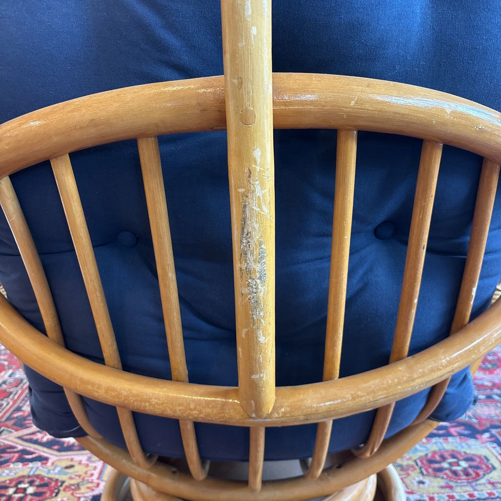 The rattan framing on a blue swivel chair, showing some wear on the wood.