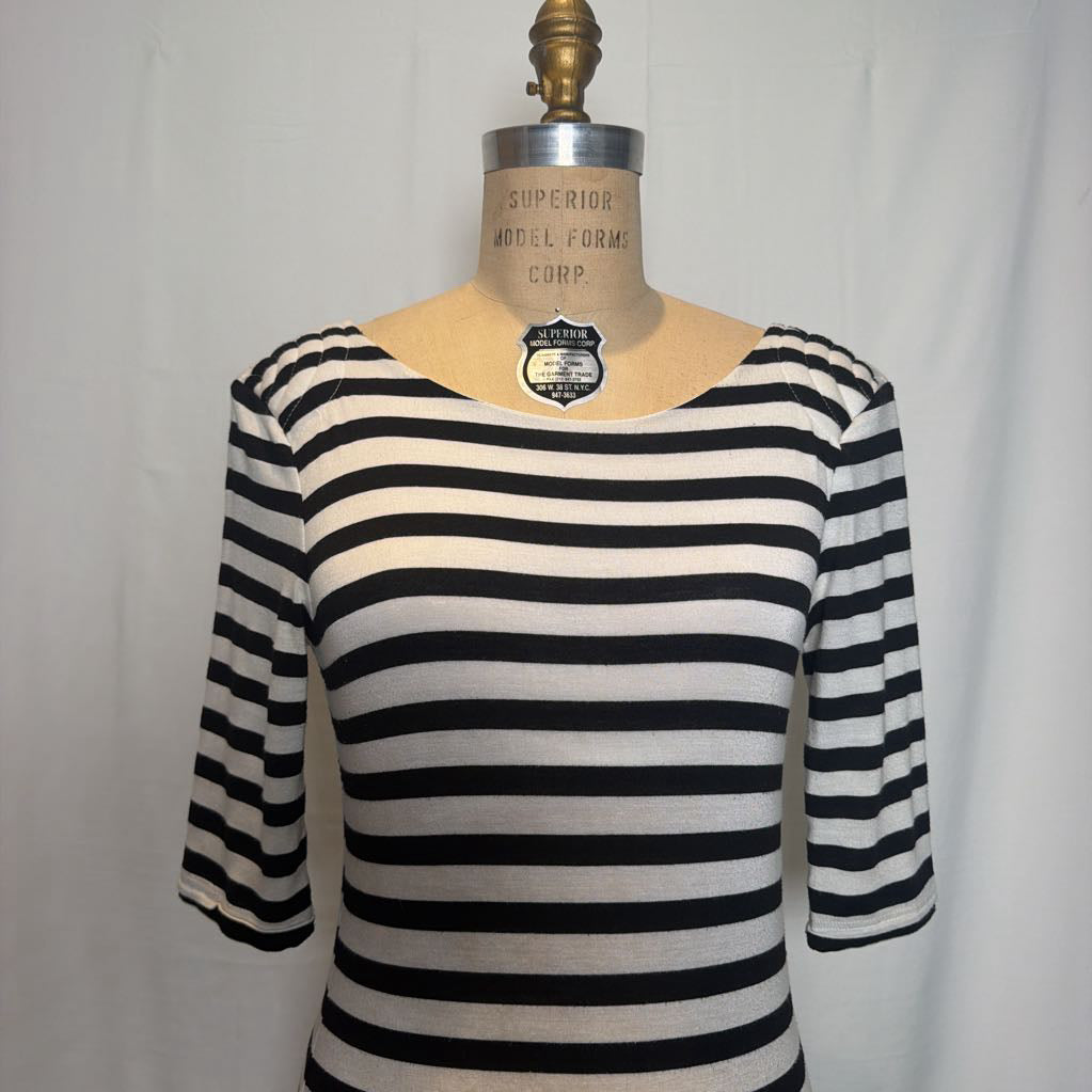 A black and off-white horizontally striped knit top displayed on a beige dress form mannequin against a white fabric backdrop.