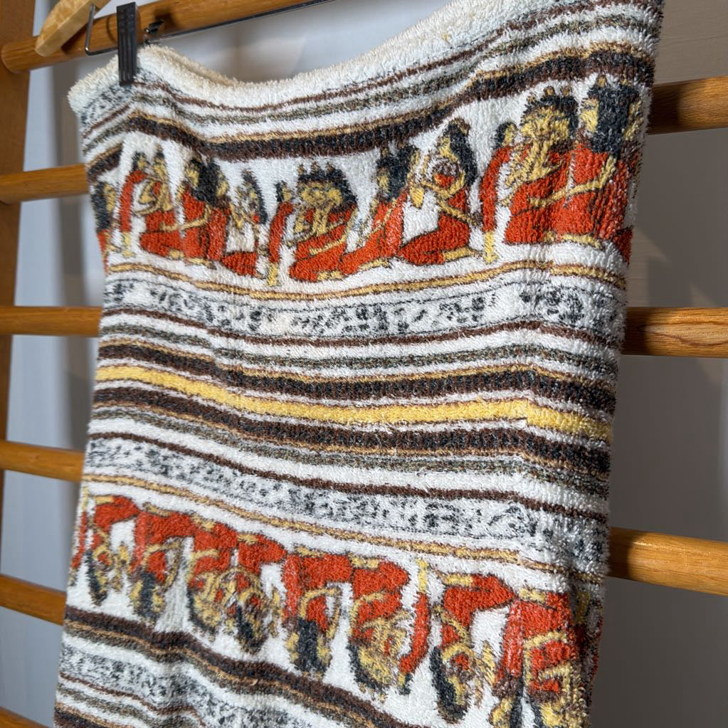 A close-up of a textured knit garment, likely a sweater or scarf, featuring horizontal stripes with cartoon-style figures in red, black, yellow, and white.