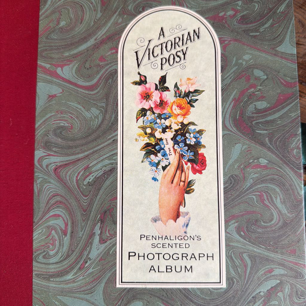 A vintage-style photo album titled "A Victorian Posy" by Penhaligon's, featuring a floral illustration on the cover with a marbled green, gray, and pink background.
