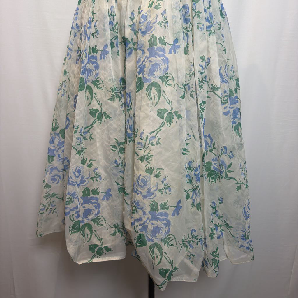 A sheer white tulle skirt featuring a blue and green floral rose pattern, displayed against a white fabric backdrop.