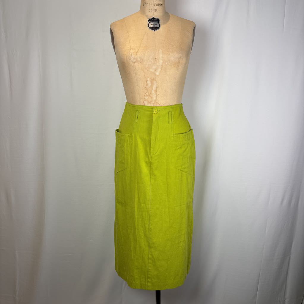 A bright lime green linen pencil skirt displayed on a beige dress form mannequin against a white fabric backdrop.
