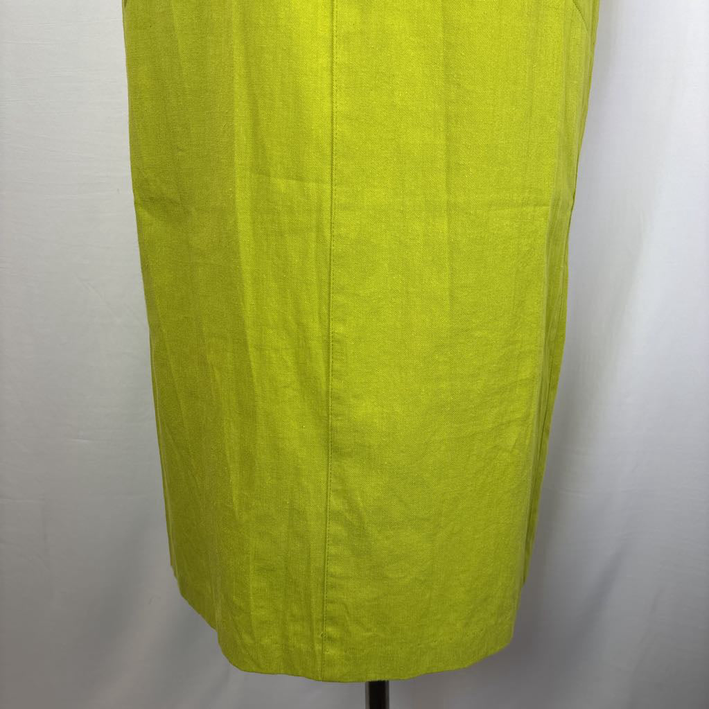 A close-up of a bright yellow-green linen skirt or dress panel displayed on a mannequin against a white fabric backdrop.