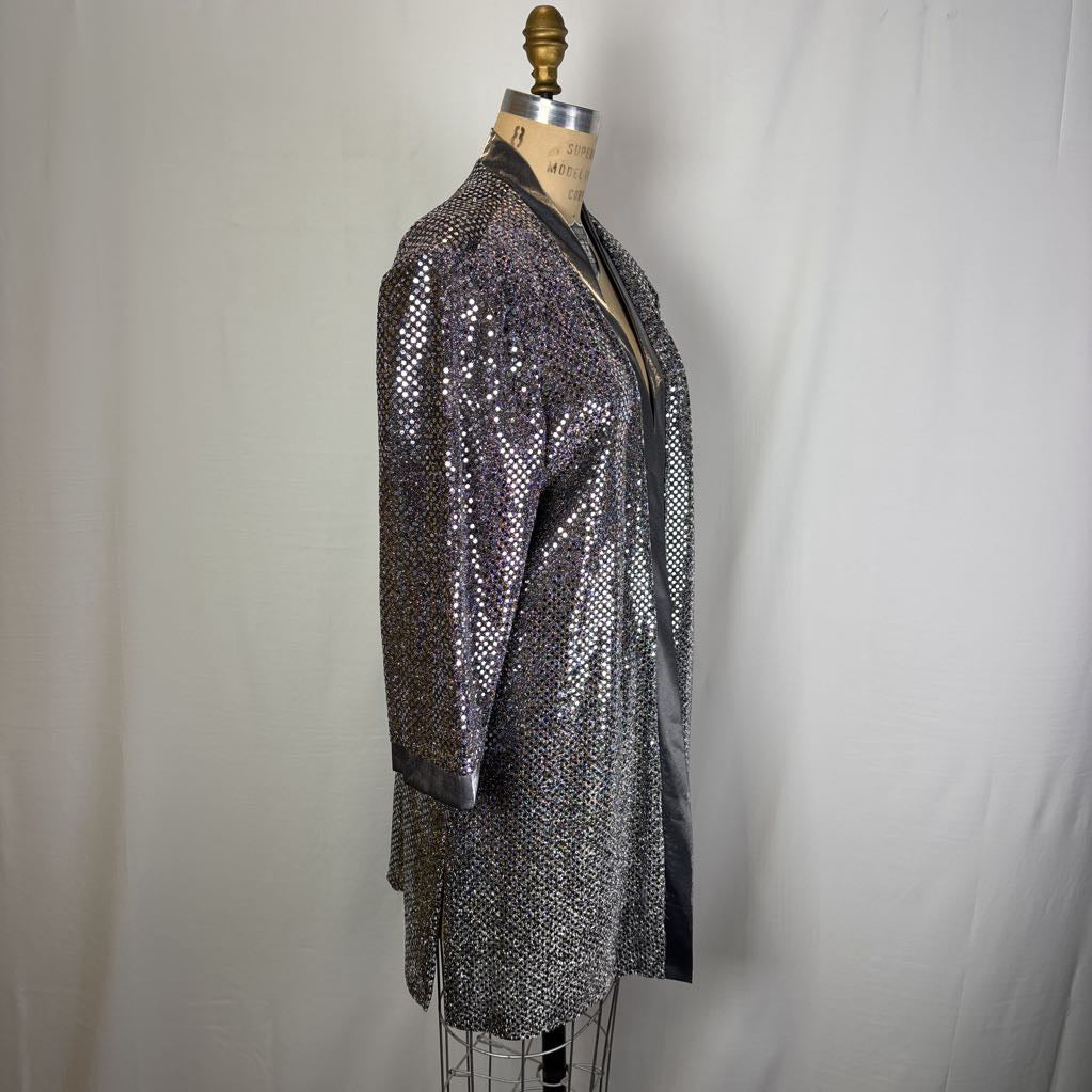 A shimmering silver sequined kimono-style jacket displayed on a dress form mannequin against a white fabric backdrop.
