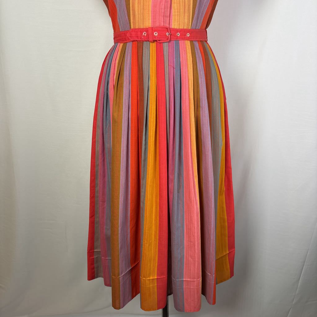 A multicolor striped dress displayed on a mannequin against a light gray fabric backdrop. The dress features vertical stripes in pink, orange, yellow, red, and blue, with a matching pink belt at the waist.
