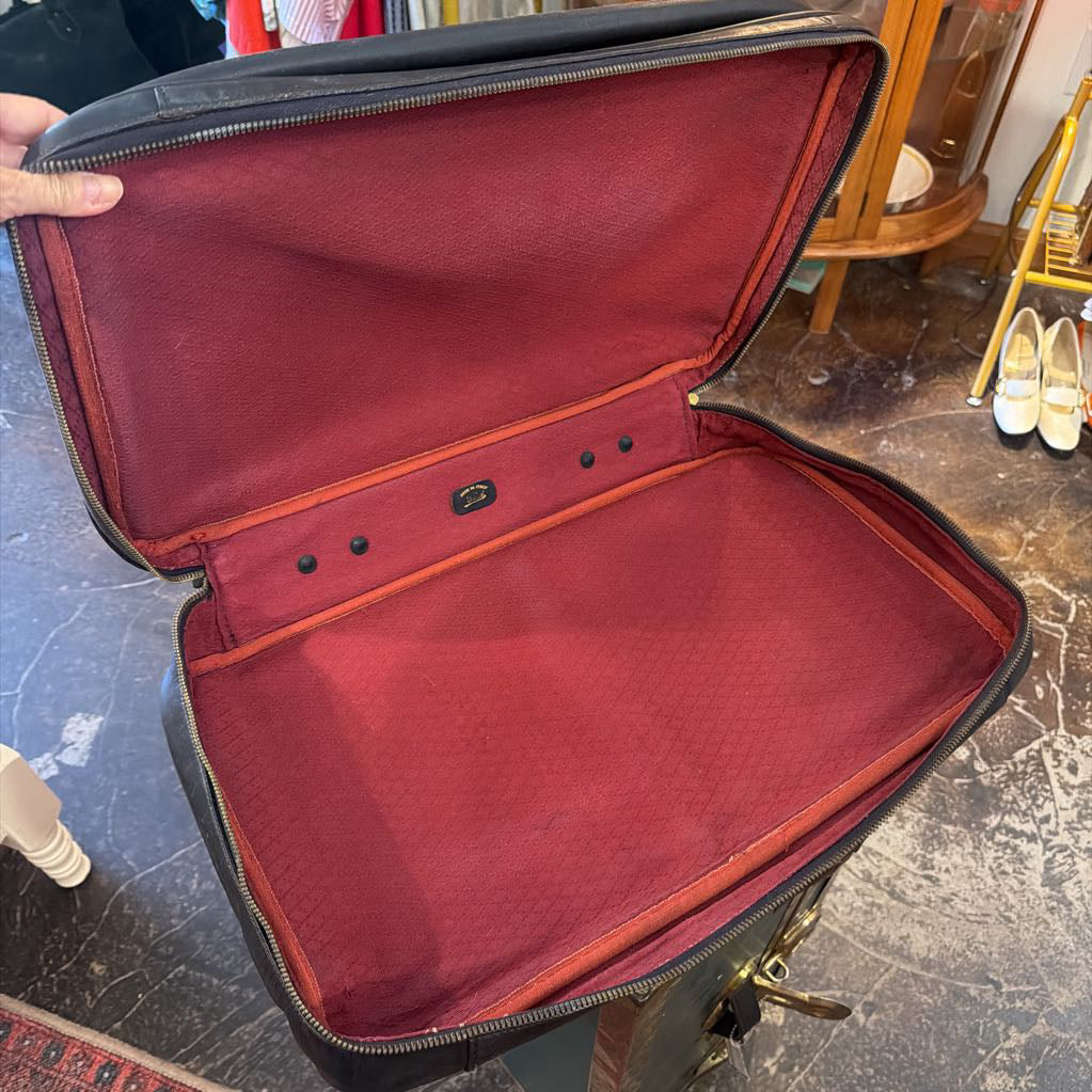 An open vintage suitcase with a dark brown exterior and a deep burgundy red interior lining, shown in a shop setting.