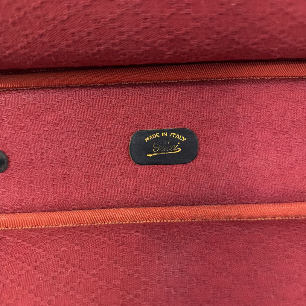 Close-up of a red textured fabric interior with orange-brown piping and a small black Gucci 'Made in Italy' label.