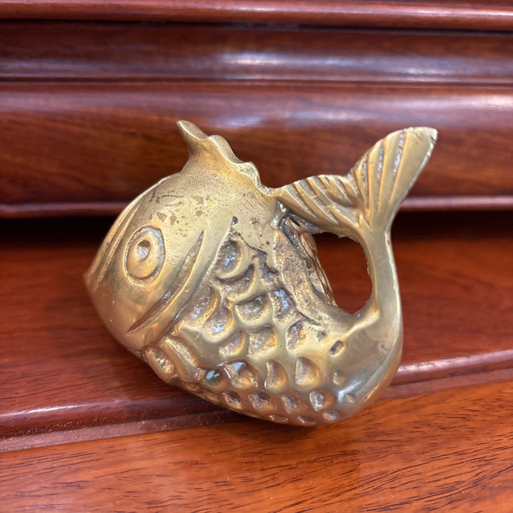 A brass fish figure on a brown wooden surface.