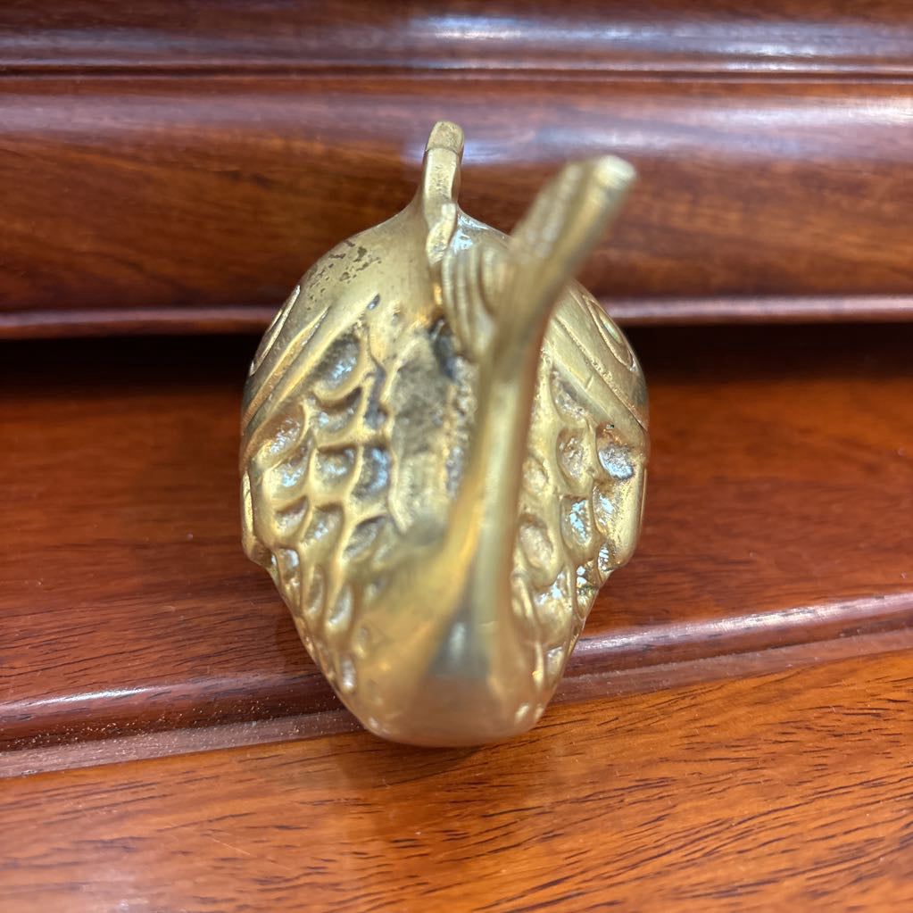A brass fish figure on a brown wooden surface.