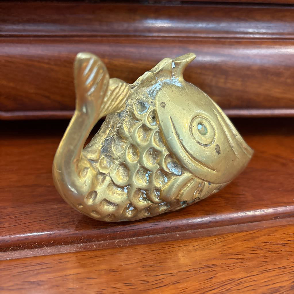A brass fish figure on a brown wooden surface.