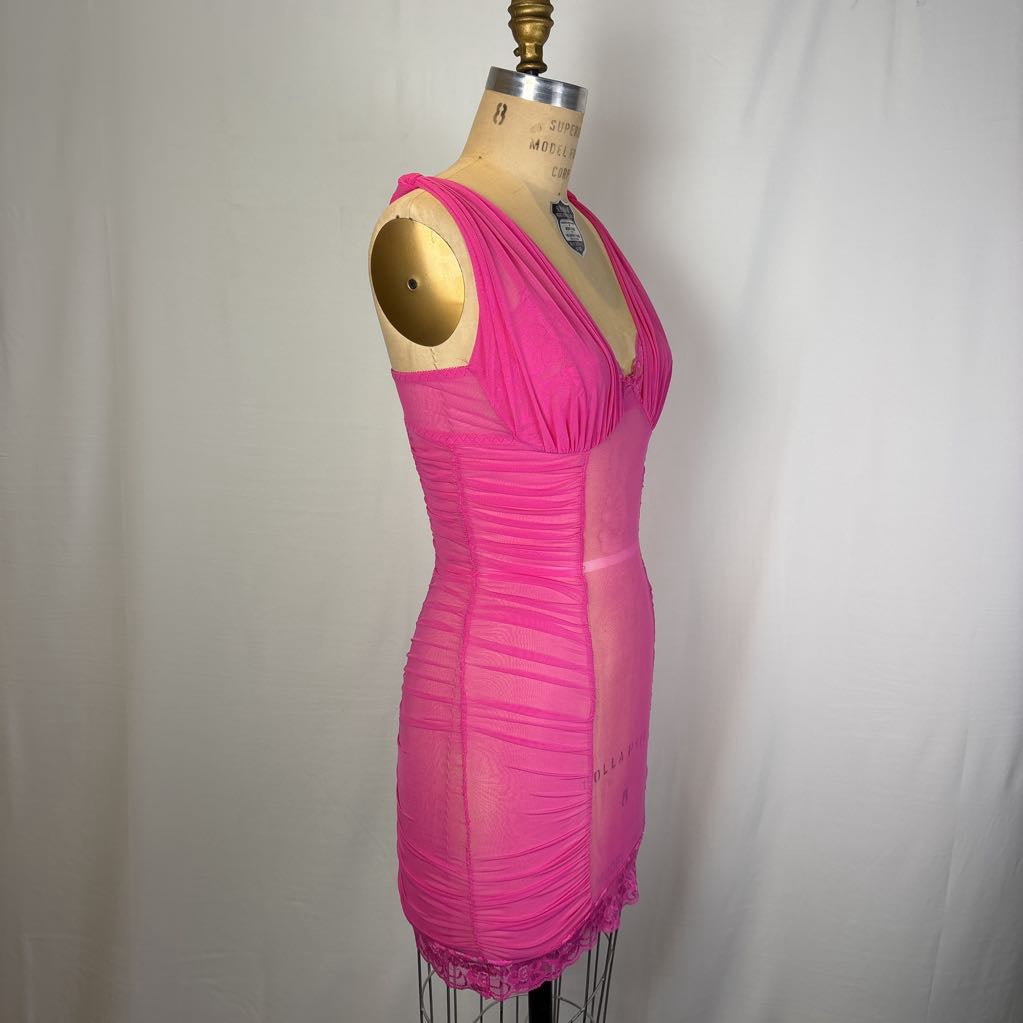 A bright pink ruched mini dress displayed on a beige dress form mannequin against a white fabric backdrop.