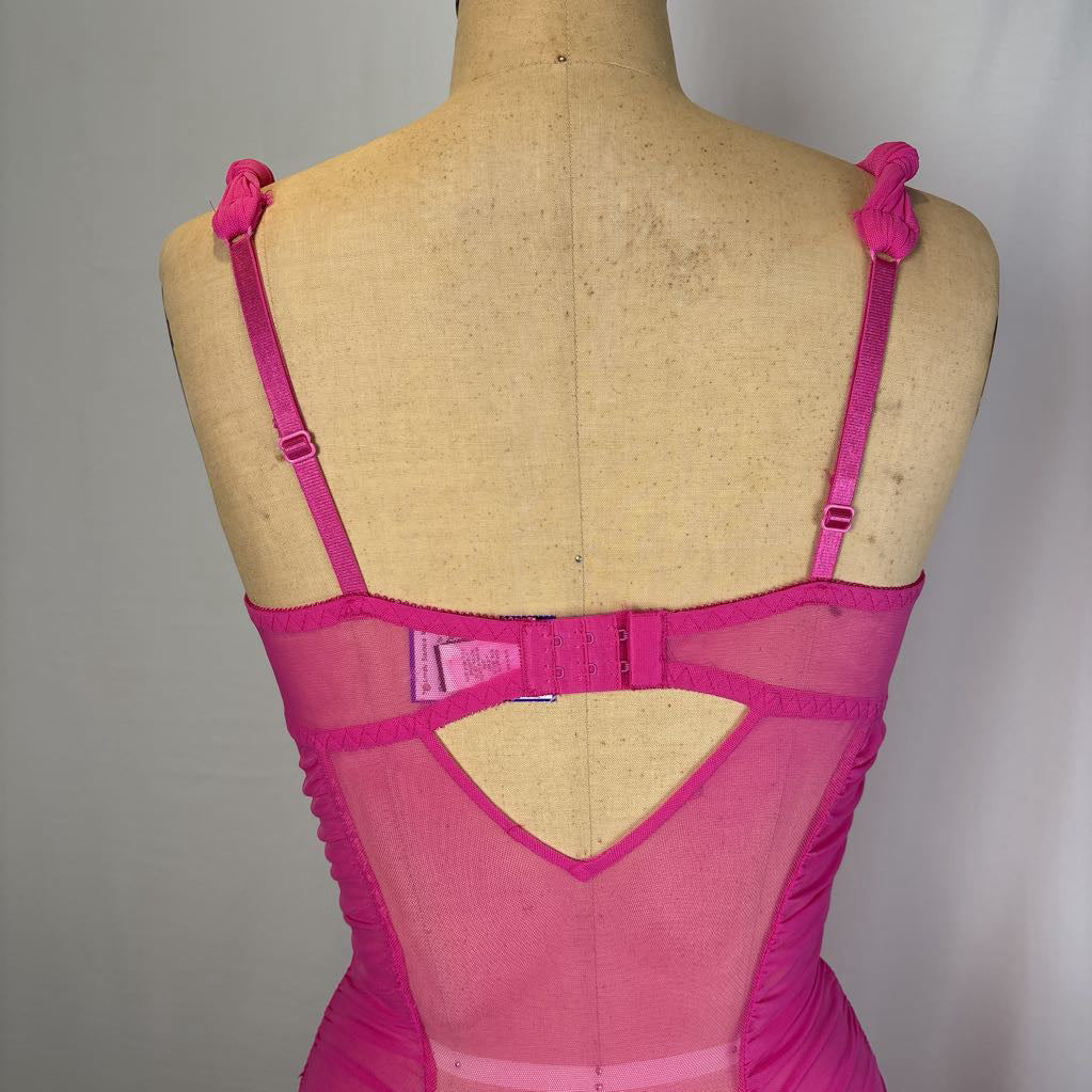 A bright pink lingerie bodysuit shown from the back on a tan dress form mannequin against a neutral gray background.