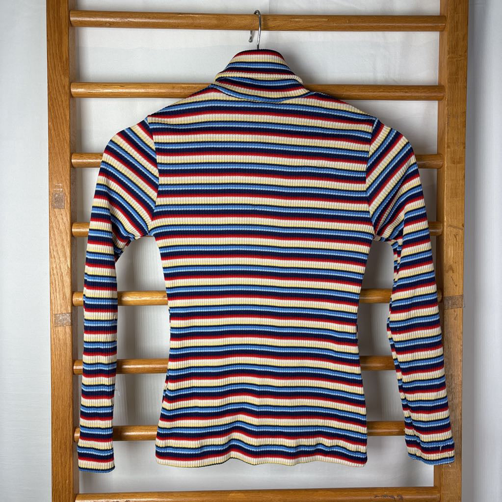 A vintage style striped turtleneck sweater on a wooden rack. 