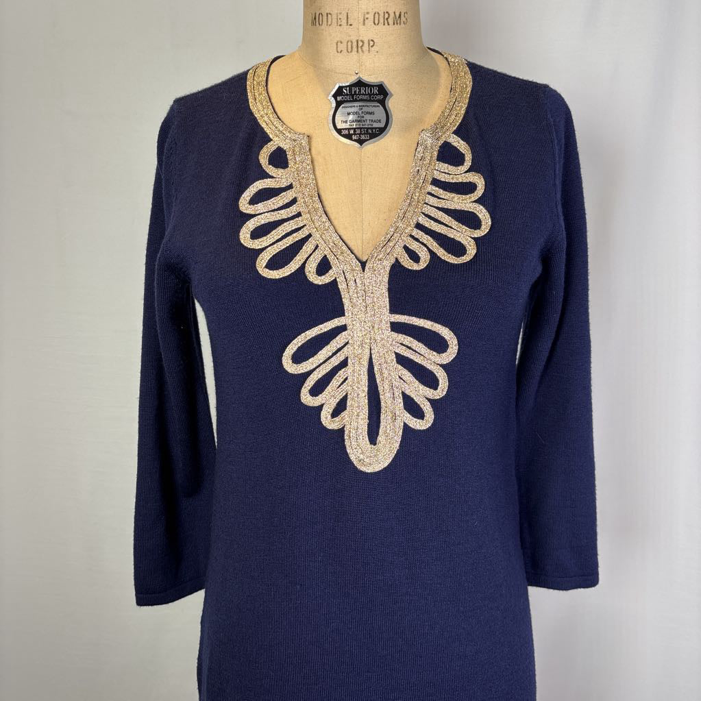 A navy blue knit tunic sweater with a beige embroidered V-neckline detail, displayed on a vintage model dress form against a light gray background.