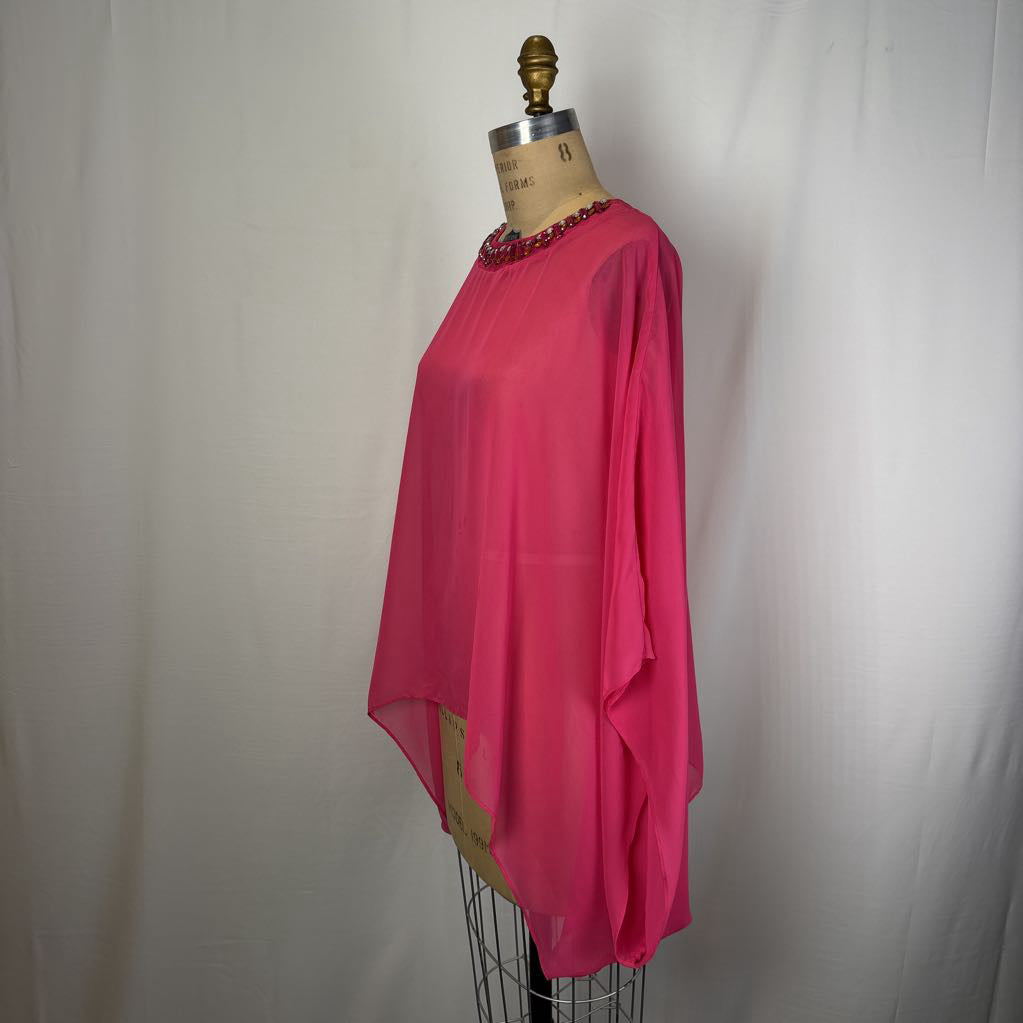 A bright pink sheer blouse with a beaded neckline, displayed on a vintage dress form mannequin against a white fabric backdrop.