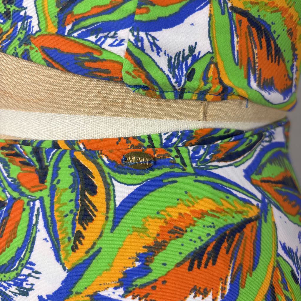 Close-up of a colorful tropical print fabric with a beige woven waistband, featuring a small gold 'Mara' brand label.