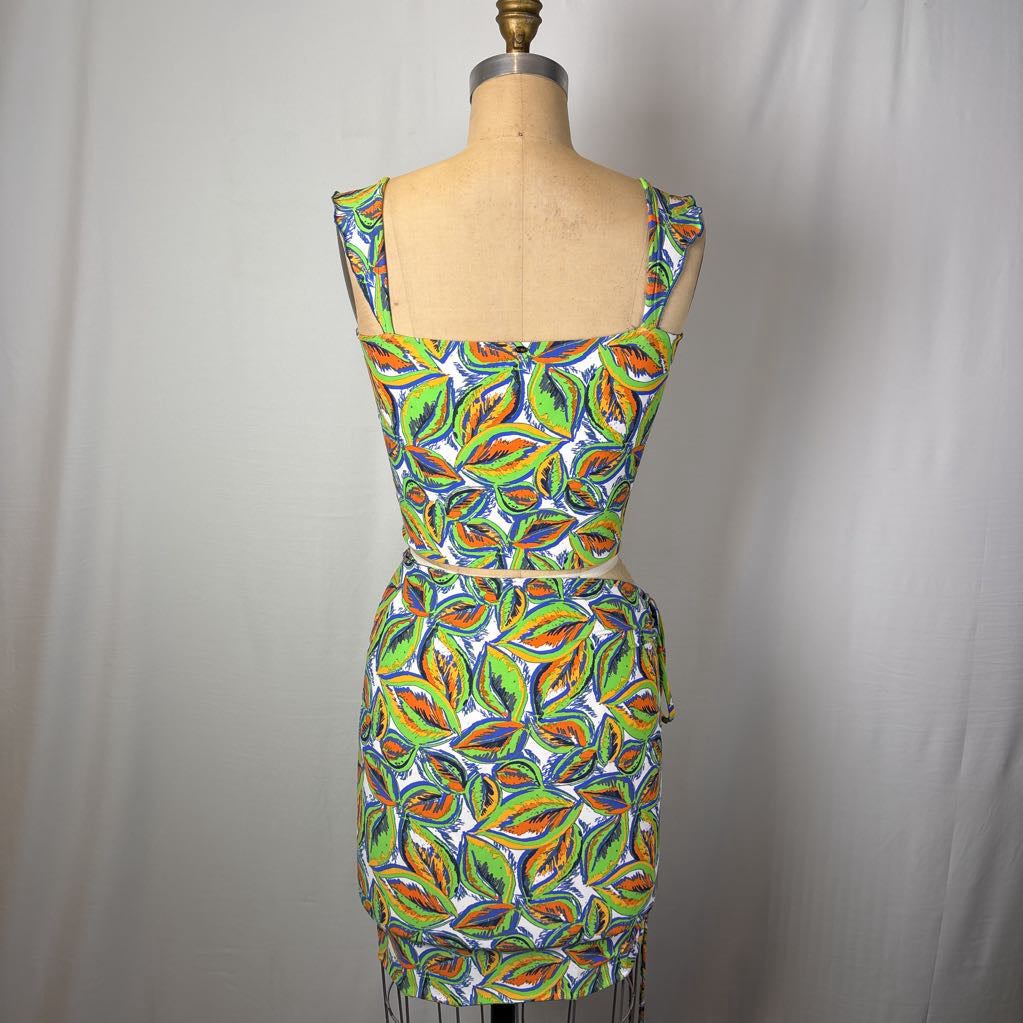 A sleeveless, scoop-neck dress displayed on a dress form, featuring a vibrant multicolor abstract pattern of green, orange, yellow, and blue shapes on a white background.