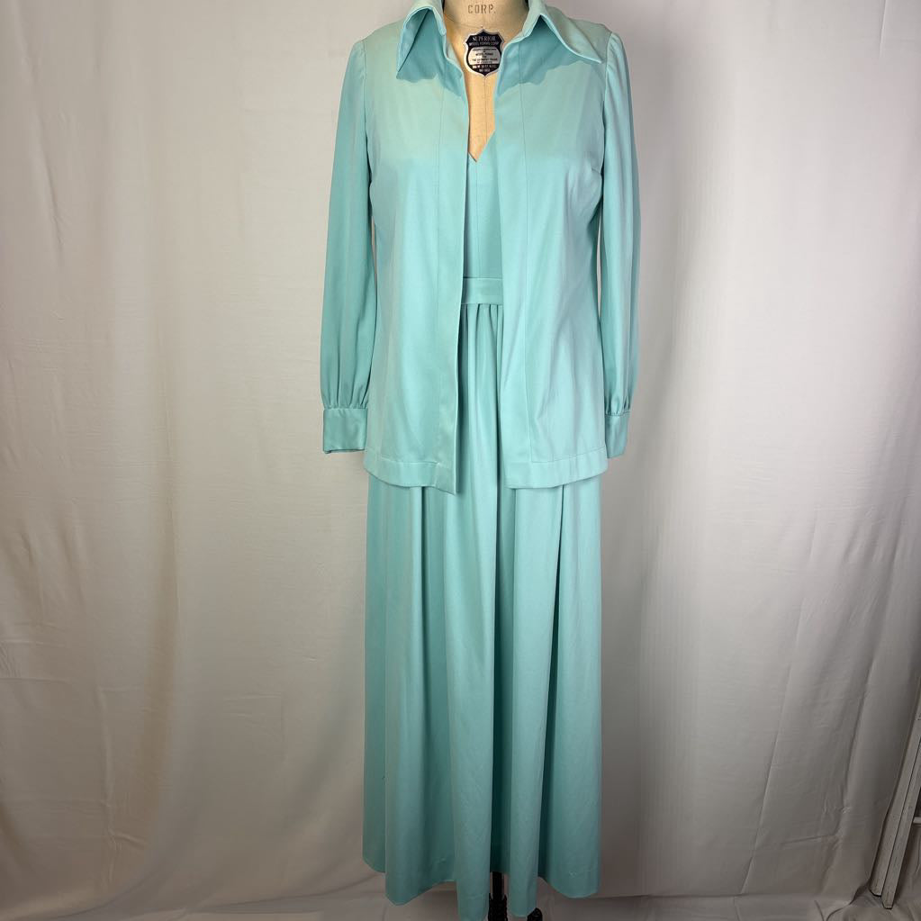 A mint green two-piece set consisting of a long-sleeve collared shirt and a matching maxi skirt, displayed on a dress form against a white fabric backdrop.