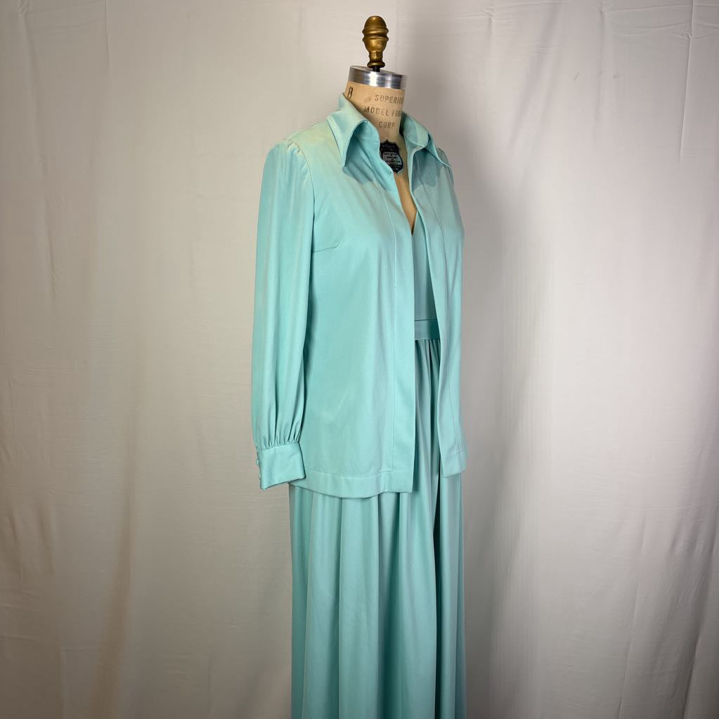 A mint green two-piece set consisting of a long-sleeve collared button-up shirt and a matching maxi skirt, displayed on a dress form mannequin against a white fabric backdrop.