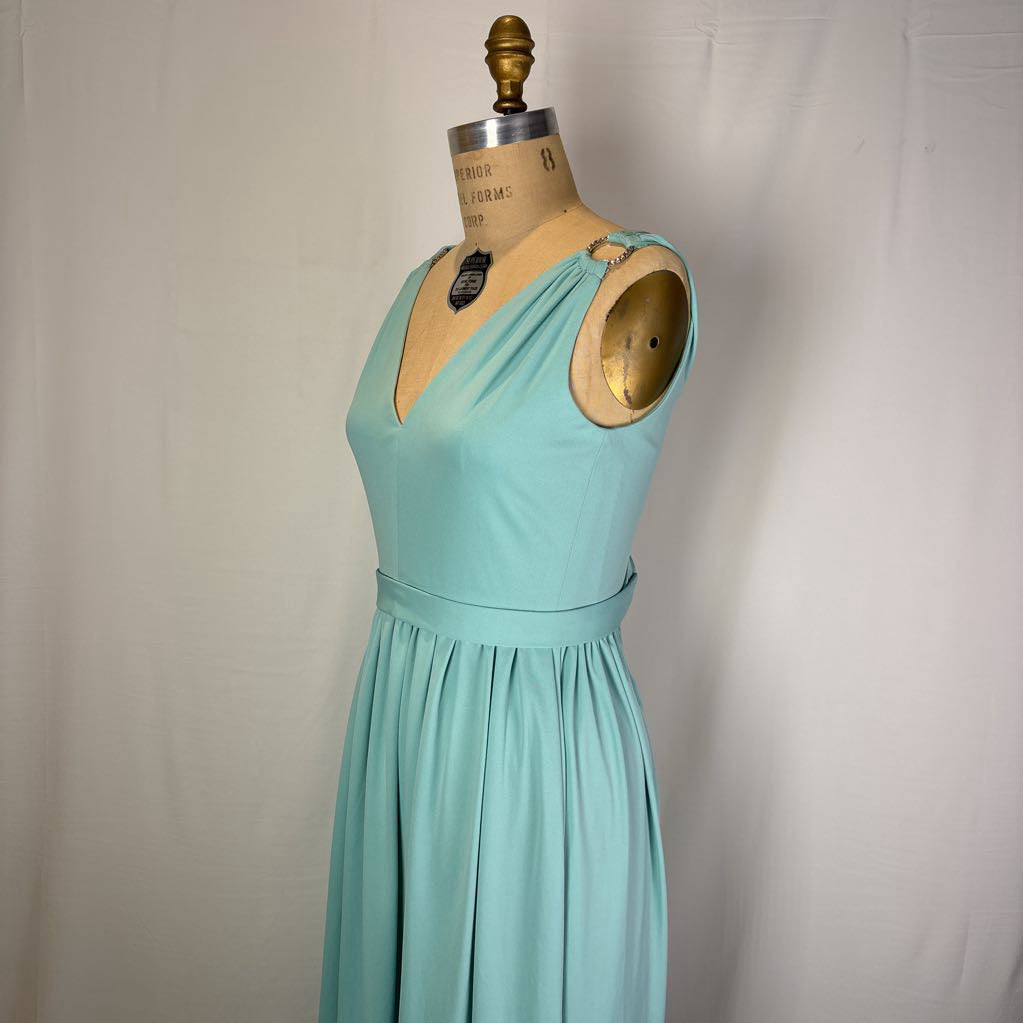 A light aqua blue sleeveless dress displayed on a vintage wooden dress form mannequin against a neutral off-white fabric backdrop.