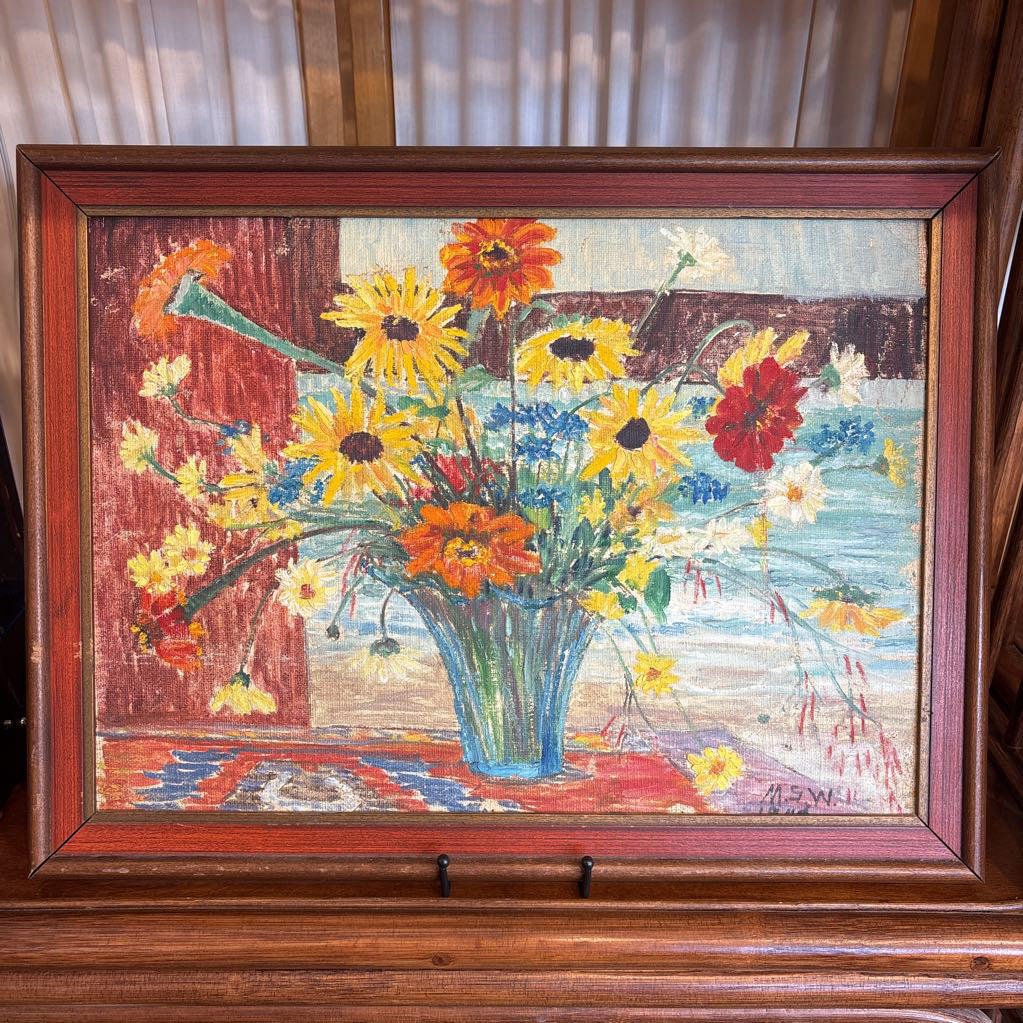 A framed still life of flowers in a vase on a wooden surface.