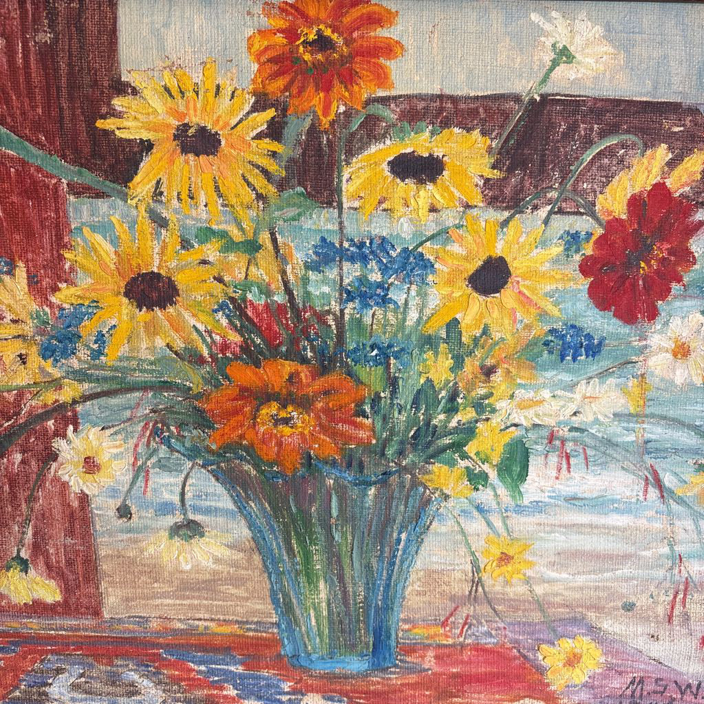 A framed still life of flowers in a vase on a wooden surface.