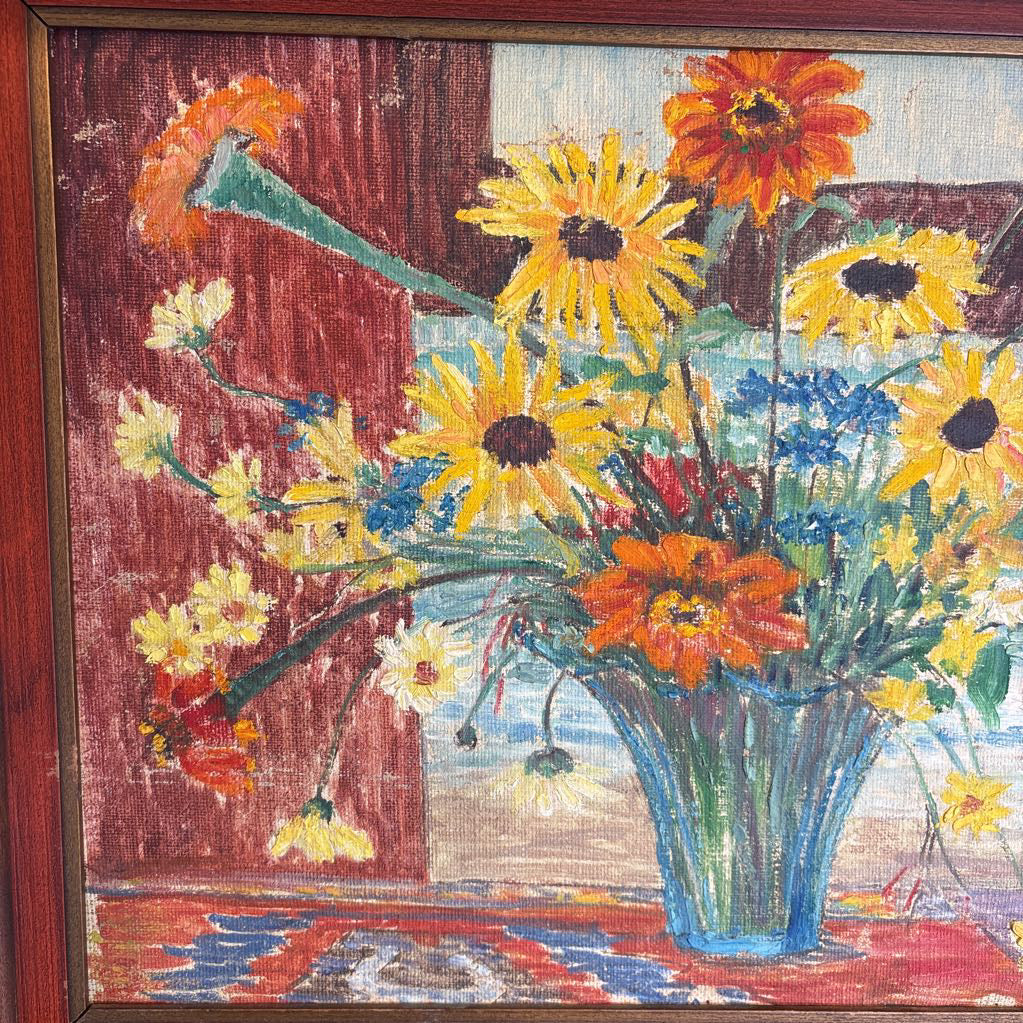 A framed still life of flowers in a vase on a wooden surface.