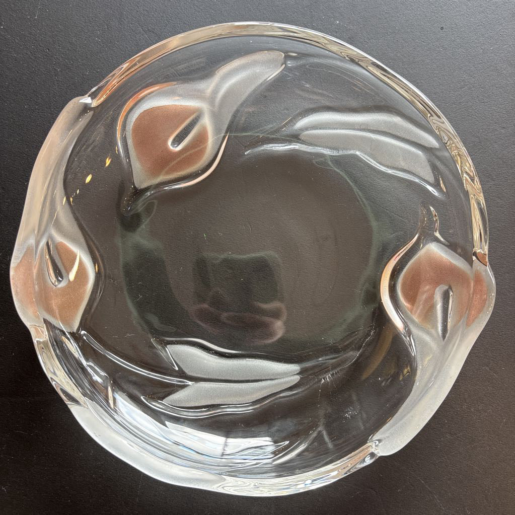 A glass plate with embossed frosted pink calla lilies sitting on a black table.