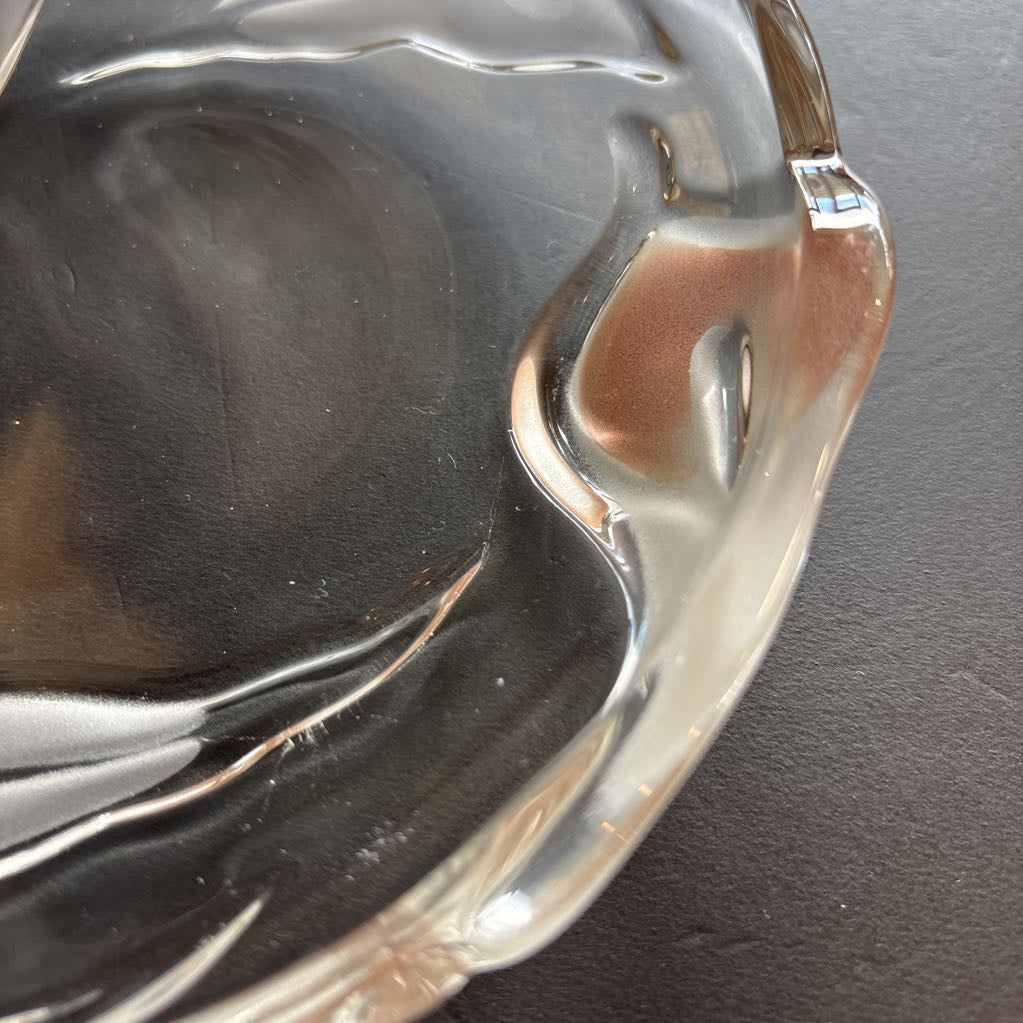 A glass plate with embossed frosted pink calla lilies sitting on a black table.