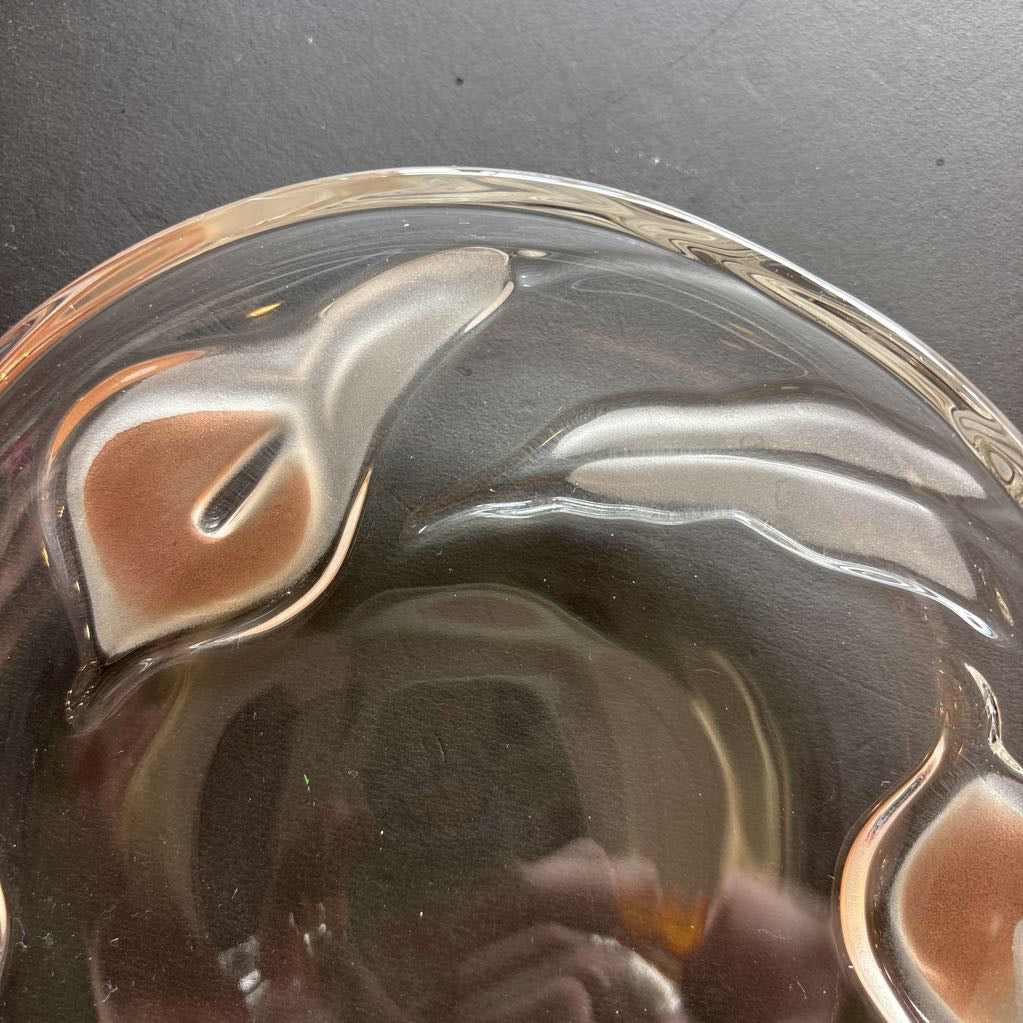 A glass plate with embossed frosted pink calla lilies sitting on a black table.