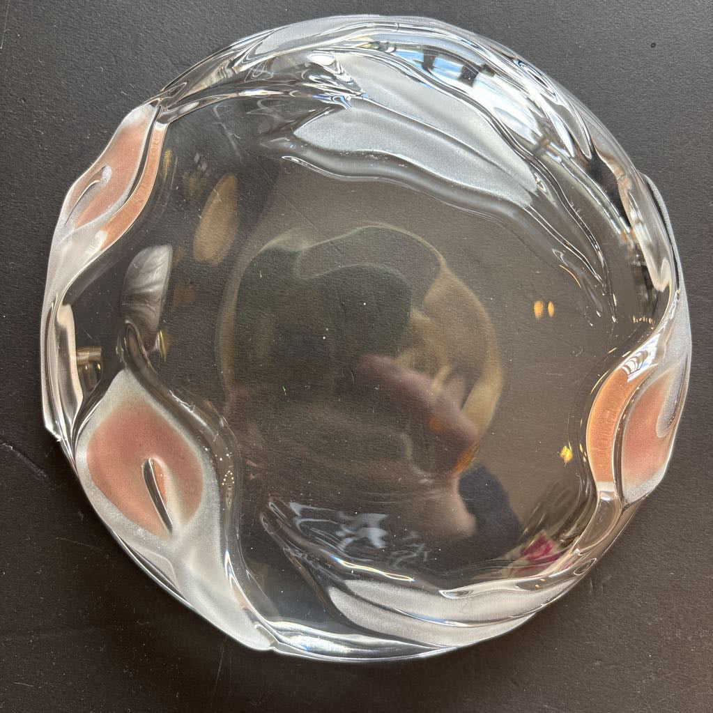 A glass plate with embossed frosted pink calla lilies sitting on a black table.
