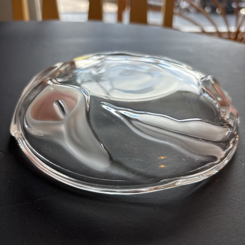 A glass plate with embossed frosted pink calla lilies sitting on a black table.