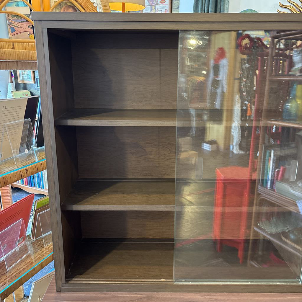 A large wooden hutch with two sliding glass doors. The cabinet is in a store setting. 